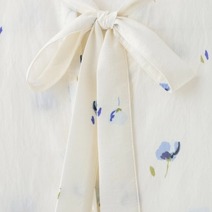 Floral print shirt with a large bow-tie neckline in cream and blue color palette