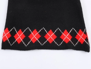 Close-up of knitted Christmas sweater featuring black and red argyle patterns and ribbing