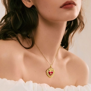 Close-up of vintage gold necklace with ruby red heart pendant worn by a model
