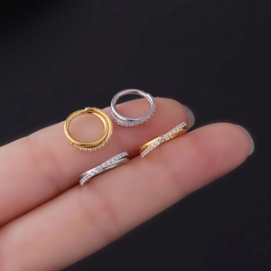 Minimalist stainless steel crisscross nose rings with zircons shown on a finger