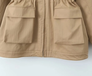 Detail view of khaki utility jacket showing drawstring waist and large patch pockets