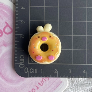 Macro shot of 2.5cm yellow resin donut accessory with cartoon animal ears and paw print