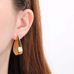 Vue macro de boucles d'oreilles goutte dorées avec une finition polie miroir brillante