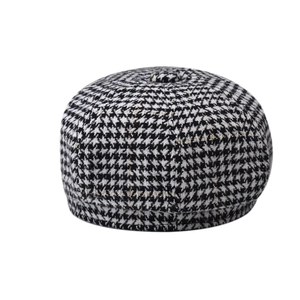 Close-up of black and white houndstooth baker boy hat with gold letter embroidery