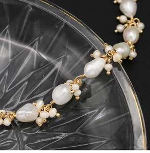 Macro shot of irregular baroque pearls and gold chain on decorative glass dish