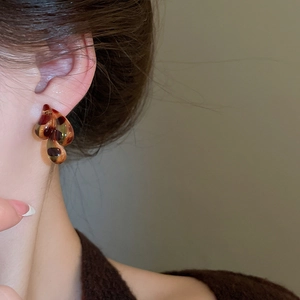 Close-up of tortoise shell resin earrings on model showing leopard pattern detail