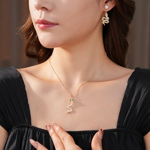 Dettaglio del set collana serpente dorata e orecchini di perle con pietre zircone