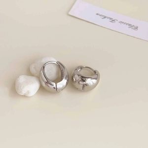 Close-up of chunky silver hoop earrings with a polished mirror finish on white stones