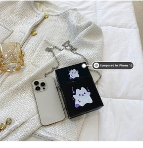 Detail view of small black ghost crossbody bag next to iPhone 12 for size comparison