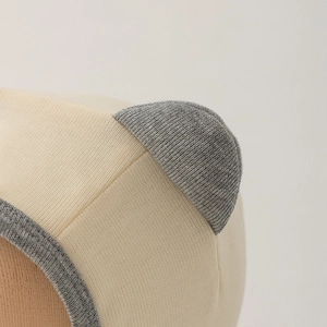 Close-up of beige and gray knitted baby hat showing cute bear ears and fabric texture