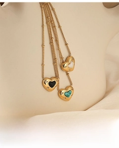 Detail of three vintage heart necklaces with black, green, and white natural stones