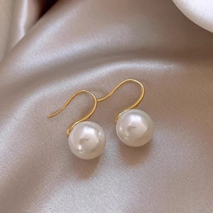 Detail of elegant gold drop earrings with white pearls on premium champagne silk fabric