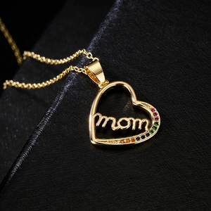 Macro shot of gold heart MOM pendant with multi-color cubic zirconia on black jewelry box