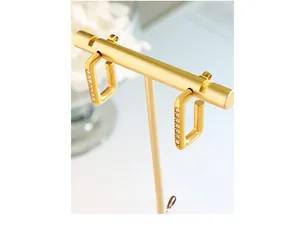 Détail de boucles d'oreilles créoles dorées rectangulaires serties de zircons fins