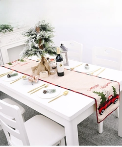 Detail of Christmas table runner with red truck and pine tree print on linen texture