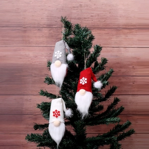 Three plush Christmas gnome ornaments hanging on a tree with knit hats and faux fur beards