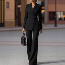 Dettaglio del blazer nero con fibbia in metallo laterale e pantaloni a gamba larga