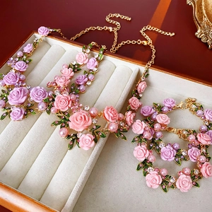 Détail parure collier et bracelet fleurs roses avec perles dans un coffret en bois