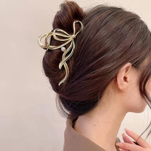 Elegant gold metal bow hair claw clip with pearl tassel shown on model hair