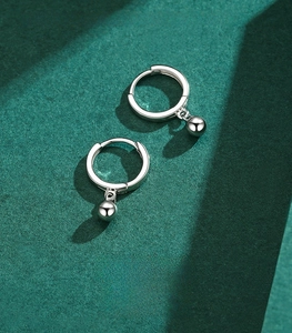 Macro shot of S925 sterling silver hoop earrings with polished bead pendants on dark green matte