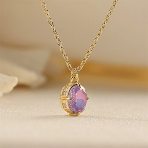 Golden necklace with purple oval glass pendant and crystal halo on soft background