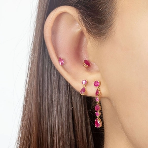 Macro detail of pear-shaped red zircon earrings in elegant gold claw setting