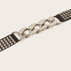 Detail of elastic wide belt featuring silver metal chains and black studded leather accents