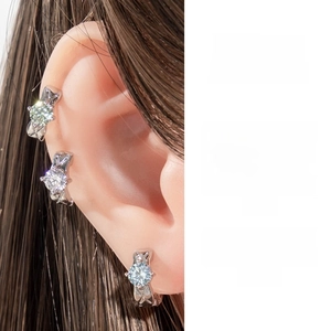 Macro shot of silver cuff earrings with claw-set round brilliant zircons and textured metal