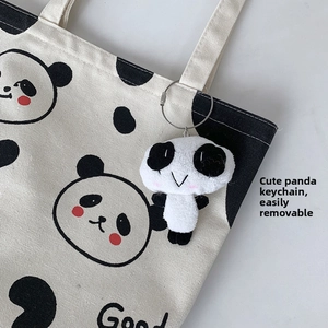 Nahaufnahme der weißen Panda-Stofftasche mit einem süßen Plüsch-Panda-Anhänger