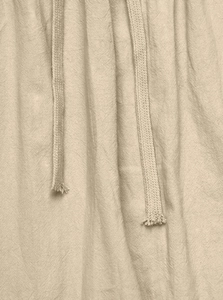 Macro shot of linen trousers featuring beige woven drawstrings and natural fiber texture