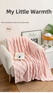 Cozy pink checkered plush blanket draped over a modern white sofa in a warm living room