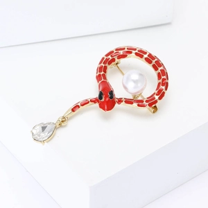 Exquisite gold snake brooch with red enamel and pearl accent on a clean white background