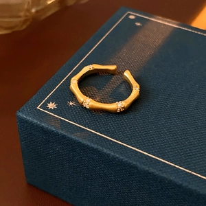 Close-up of golden bamboo-style open ring with sparkling zircon stones on a jewelry box