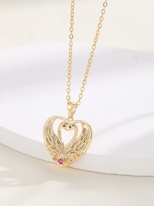 Close-up of golden heart pendant featuring two swans and a sparkling pink gemstone