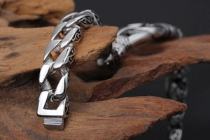 Detail of vintage stainless steel chain bracelet with floral carvings on weathered wood
