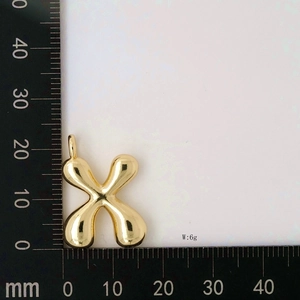 Macro shot of gold letter X balloon pendant measuring 30mm with 6g weight label