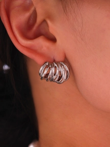 Macro shot of silver multi-layer curved line earrings on model ear for detailed view
