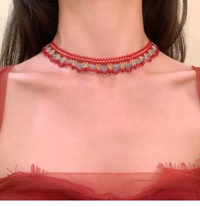 Gros plan du collier choker fait main en perles de cristal sur mannequin en rouge