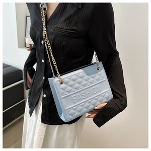 Detail of light blue quilted bag with fashion embossing and golden chain strap
