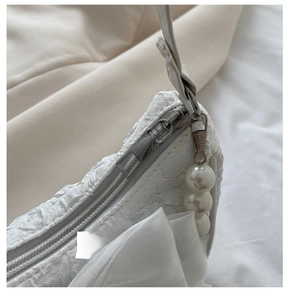 Detail of smooth silver zipper with pearl pendant on white pleated fashion handbag