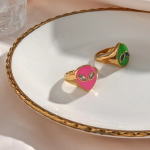Detail of pink and green enamel alien rings with 18K gold plating on a white plate