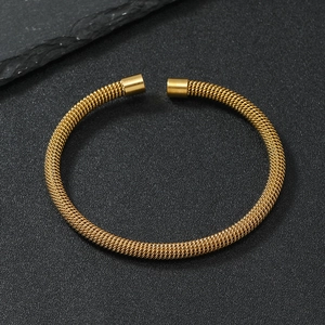 Detailed close-up of golden mesh wire texture on a stainless steel open cuff bracelet