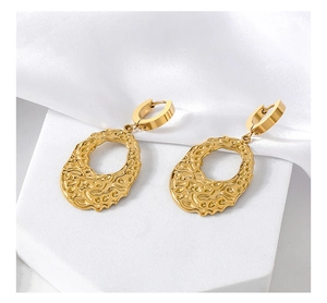 Detail of gold irregular oval earrings with hammered texture on white silk backdrop