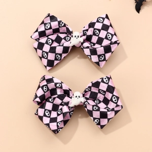 Close-up of pink and black plaid Halloween bow hair clips with white ghost dolls