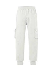 Detailed view of white quilted cargo pants with waffle texture and elastic drawstring waist