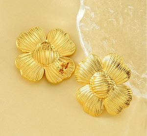 Detail of vintage gold flower earrings on beige silk with ice props and soft lighting