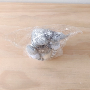 Close-up of a Christmas gnome doll with grey knit hat wrapped in transparent plastic bag