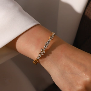 Bracelet jonc ouvert en acier doré avec zircons rectangulaires porté sur le poignet