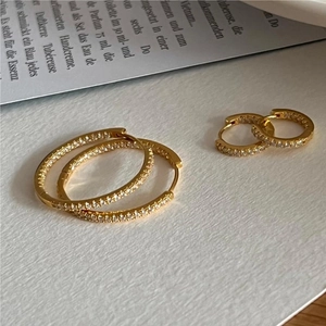 Minimalist gold plated hoop earrings set with sparkling cubic zirconia on a white table