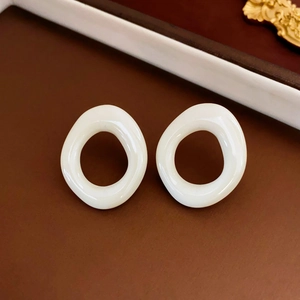 Close-up of white oval resin earrings with glossy finish on a vintage prop background